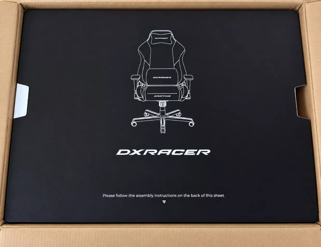 Carton DXRacer ouvert avec la notice de montage sur le dessus